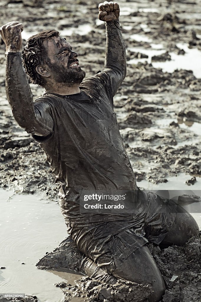 Dark haired man celebrating during a mud run