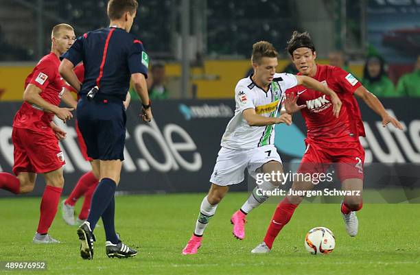Jeong-Ho Hong of Augsburg tackles Patrick Herrmann of Moenchengladbach during the Bundesliga match between Borussia Moenchengladbach and FC Augsburg...