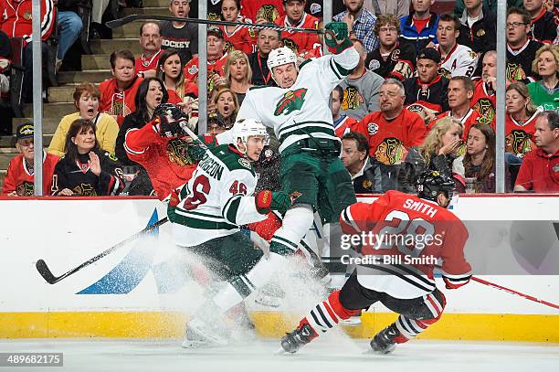 Cody McCormick of the Minnesota Wild slams into the boards, behind teammate Jared Spurgeon and Ben Smith of the Chicago Blackhawks in Game Five of...