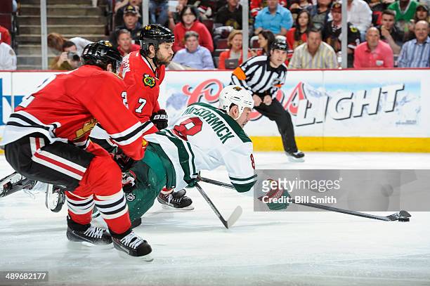Cody McCormick of the Minnesota Wild reaches for the puck as Brent Seabrook of the Chicago Blackhawks chases behind in Game Five of the Second Round...