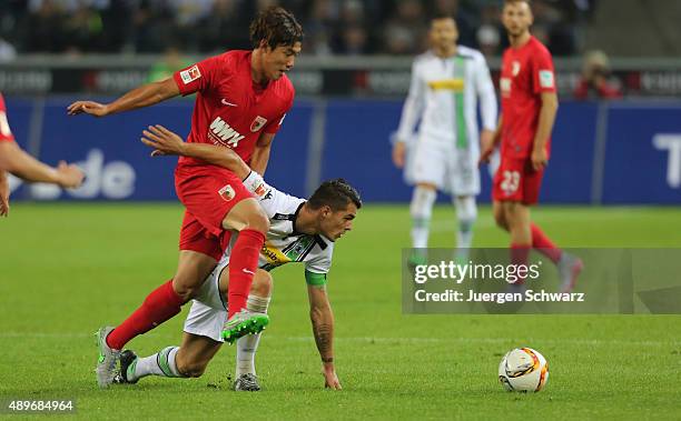 Jeong-Ho Hong of Augsburg tackles Granit Xhaka of Moenchengladbach during the Bundesliga match between Borussia Moenchengladbach and FC Augsburg at...