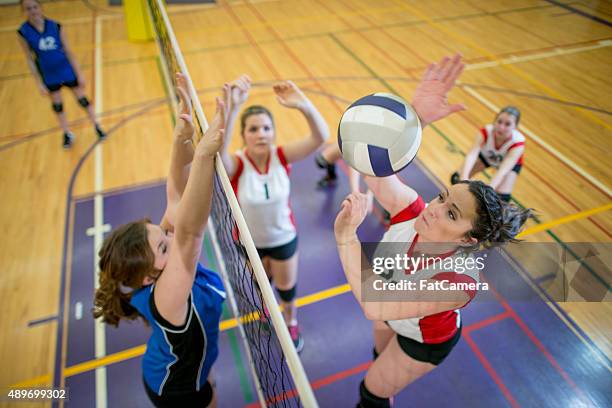 women spiking and blocking a volleyball - volleyball stockfoto's en -beelden