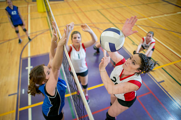 women spiking and blocking a volleyball - girls volleyball stock pictures, royalty-free photos & images