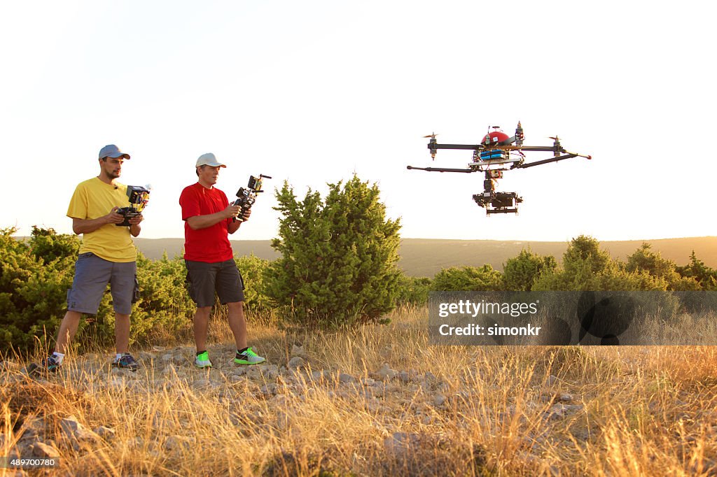 Men flying drone at sunset