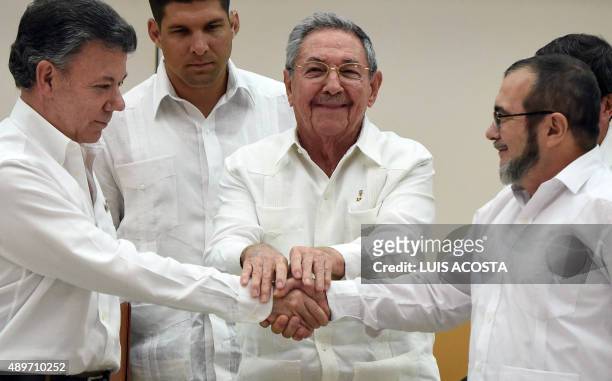 Colombian President Juan Manuel Santos and the head of the FARC guerrilla Timoleon Jimenez, aka Timochenko , shake hands as Cuban President Raul...