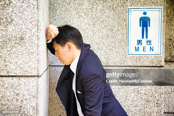 suffering japanese businessman rests against wc wall feeling sick - restroom sign 個照片及圖片檔