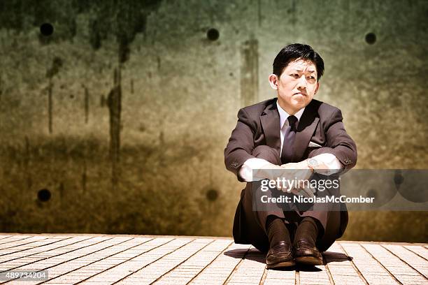 depressed japanese businessman sits and looks away - foetushouding stockfoto's en -beelden