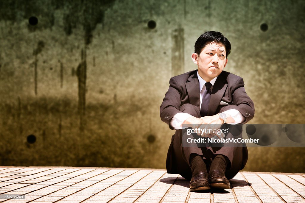 Depressed Japanese businessman sits and looks away
