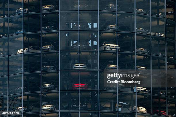 Automobiles, produced by Volkswagen AG , sit behind windows inside the auto delivery tower at the VW headquarters in Wolfsburg, Germany, on...