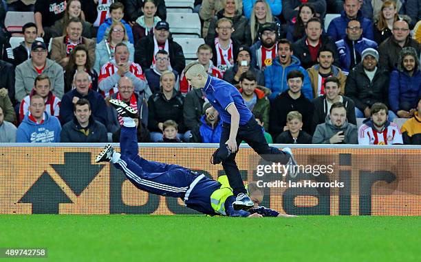 Pitch invader escapes the clutches of a steward during the Capital One Cup Third Round match between Sunderland and Manchester City at the Stadium of...