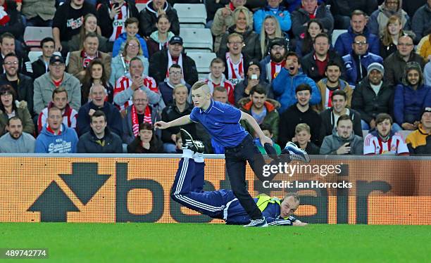 Pitch invader escapes the clutches of a steward during the Capital One Cup Third Round match between Sunderland and Manchester City at the Stadium of...