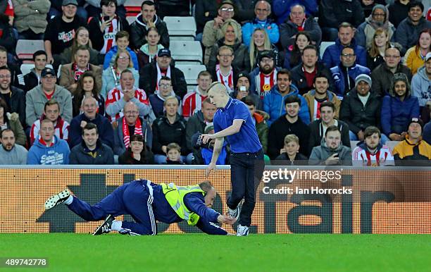 Pitch invader escapes the clutches of a steward during the Capital One Cup Third Round match between Sunderland and Manchester City at the Stadium of...