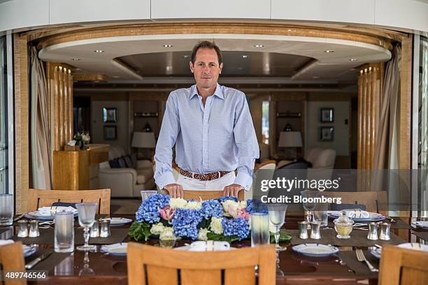 Chris Cecil-Wright, chief executive officer of Cecil-Wright and Partners yacht brokerage company, poses for a photograph beside a dining table during...