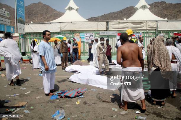 Hajj pilgrims and Saudi emergency personnel stand near bodies at the site where at least 450 were killed and hundreds wounded in a stampede in Mina,...