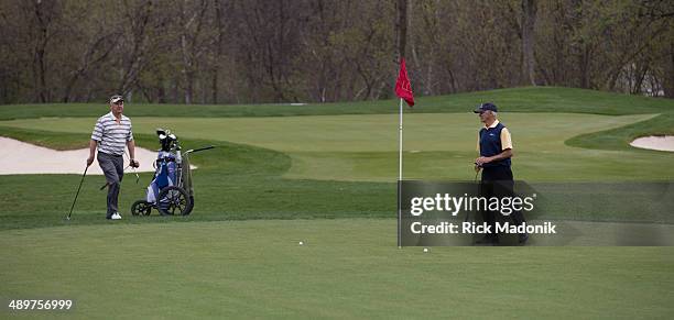 Two men, part of a foursome, walk to their ball son the temporary green on. Behind them is the full green which needs time for the sod to take....