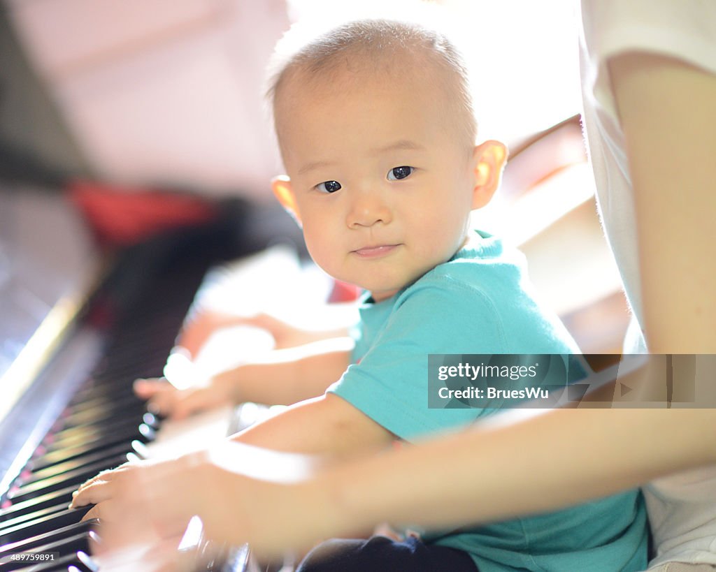 Baby playing piano with mom