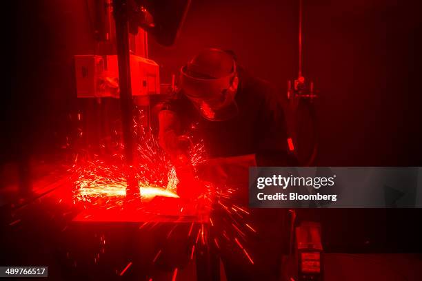 An apprentice grinds a section of metal behind the protective screen of a welding booth at Alstom SA's welding training facility in Stafford, U.K.,...