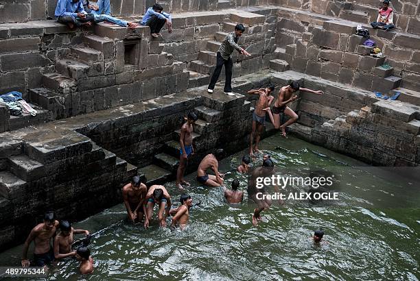 Indian youths play in the water at the bottom of the historic Chand Baori stepwell as others look on in Abhaneri village of western Rajasthan state...