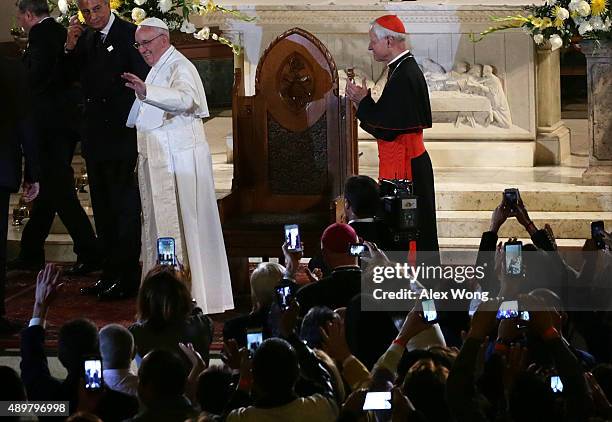 Pope Francis waves as he leaves after his visit at St. Patrick's Catholic Church as Cardinal Donald Wuerl of Archbishop of Washington looks on...