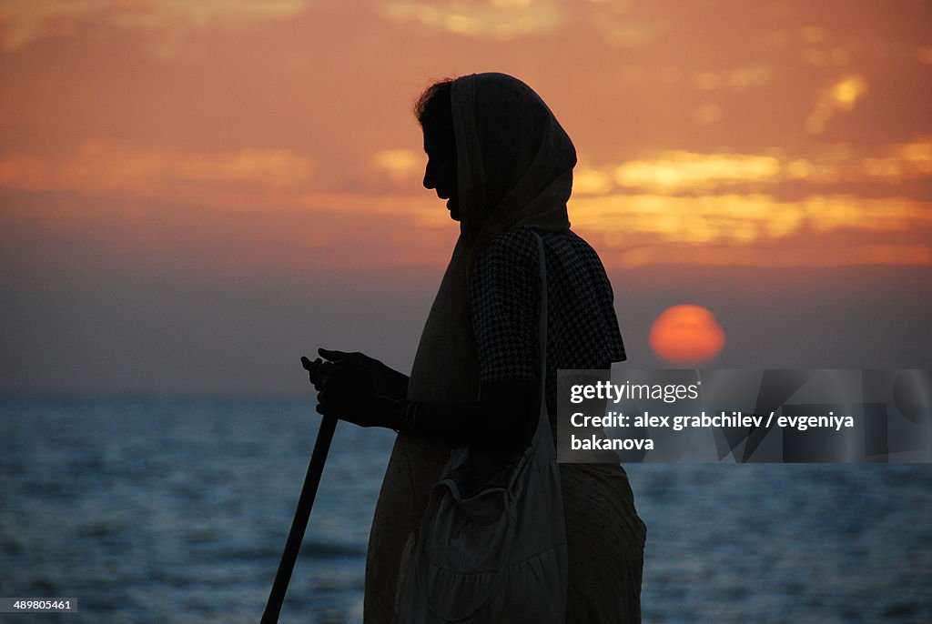 Silhouette of the old Indian woman against the sun