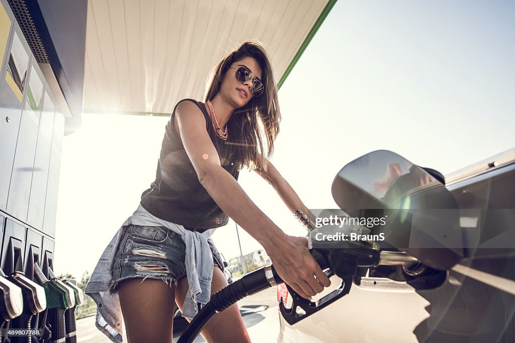 Below view of a young woman at gas station.