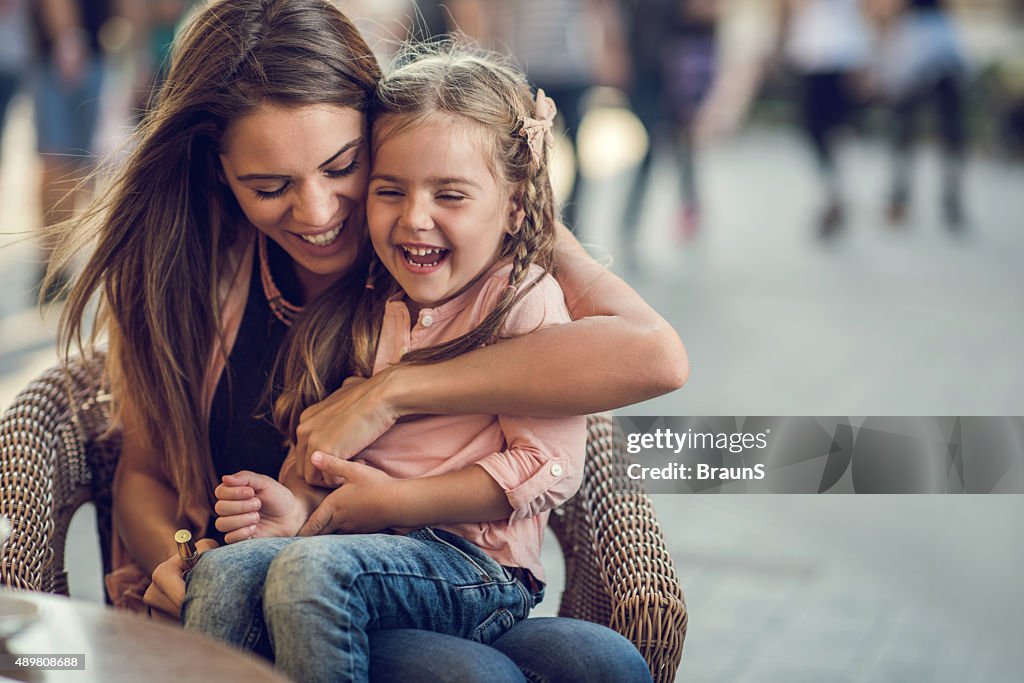 Embraced mother and daughter laughing and having fun outdoors.