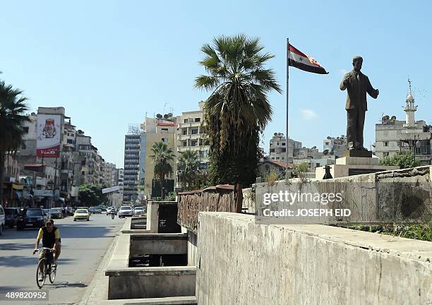 Man rides his bike past a statue of late Syrian president Hafez al-Assad, father of current President Bashar al-Assad, in the Syrian coastal city of...