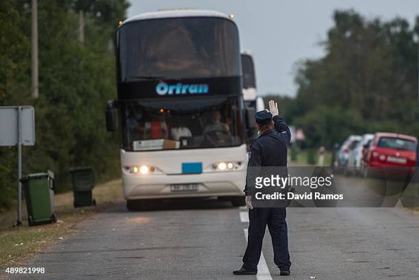 Croatian police officer stops a convoy transporting migrants as they arrive at a border point between Croatia and Hungary where they will be...
