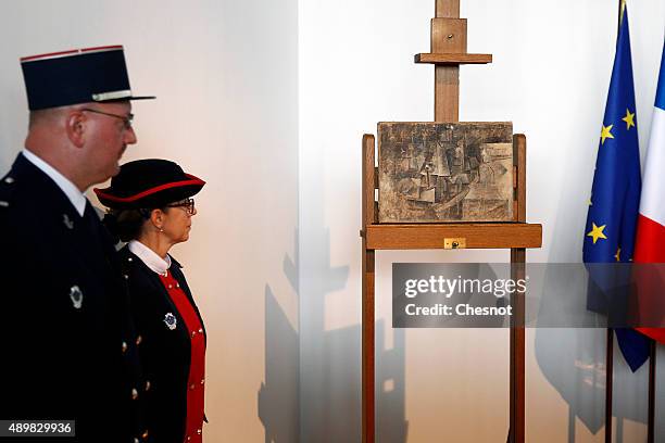 French customs officers stand guard next to an oil painting by Pablo Picasso entitled 'La coiffeuse' The hairdresser during the official presentation...