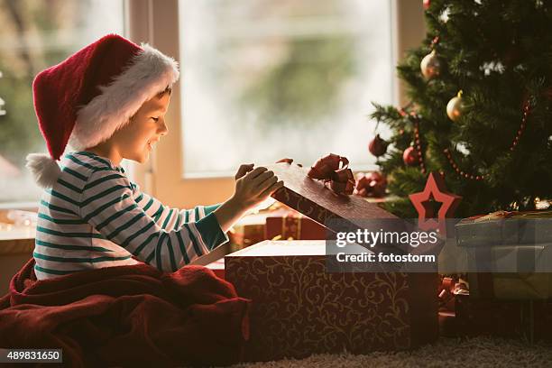 little boy opening christmas present - bois noel stock pictures, royalty-free photos & images