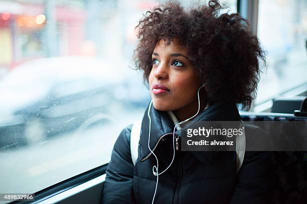 young girl listening to music on public transport - headphones woman stockfoto's en -beelden