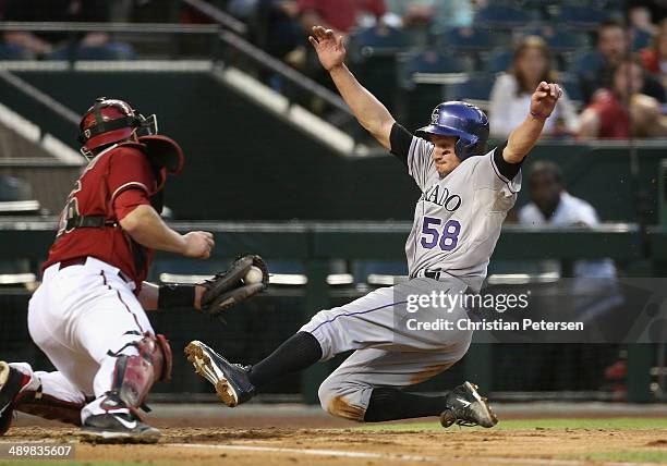 Jordan Pacheco of the Colorado Rockies slides in to score against the Arizona Diamondbacks during the MLB game at Chase Field on April 30, 2014 in...