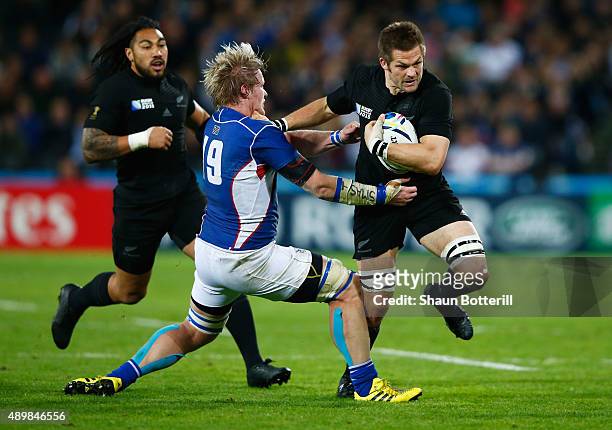 Richie McCaw of the New Zealand All Blacks is tackled by Renaldo Bothma of Namibia during the 2015 Rugby World Cup Pool C match between New Zealand...