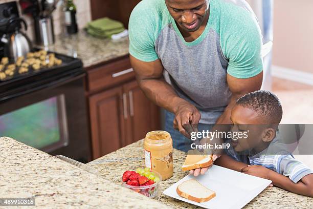 father at home making peanut butter sandwich for son - peanut butter stock pictures, royalty-free photos & images