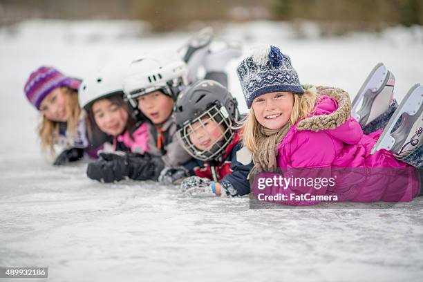 kinder in einer reihe auf dem eis - eislaufen stock-fotos und bilder