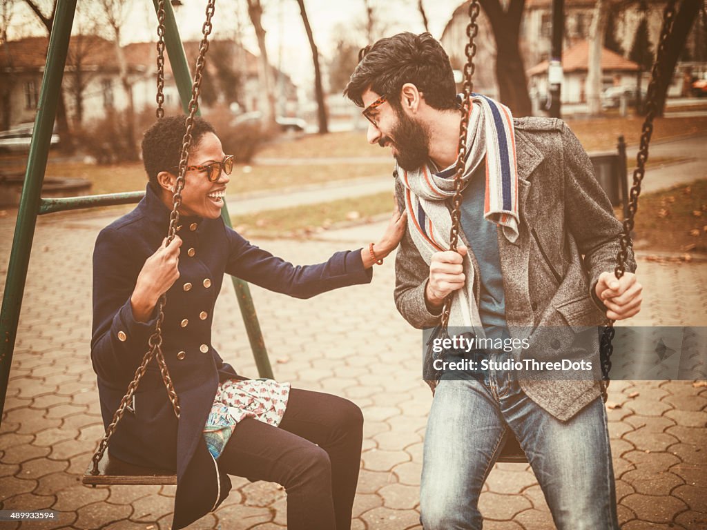 Happy mixed race couple playing on swing