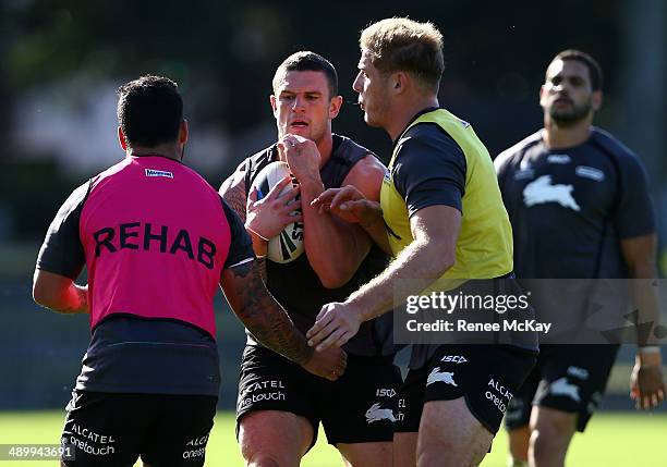 Luke Burgess is tackled by Issac Luke and George Burgess during a South Sydney Rabbitohs NRL training session at Redfern Oval on May 13, 2014 in...