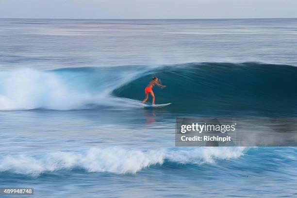 surfer girl speeds along a perfect wave - board shorts stock pictures, royalty-free photos & images