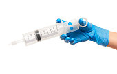 Female doctor's hand in blue surgical glove with plastic syringe