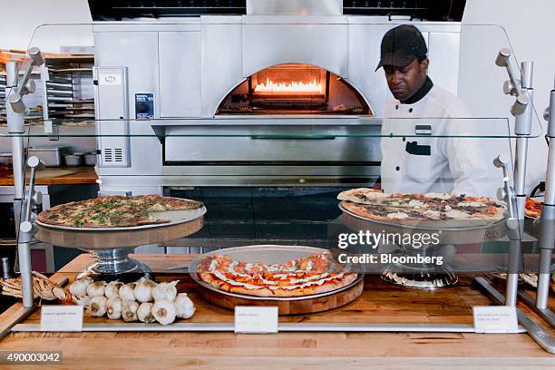 An employee prepares to serve pizza during lunch in the cafeteria of the Goldman Sachs Group Inc. Office in New York, U.S., on Thursday, Sept. 10,...