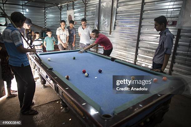 Young Syrian refugees play billiards at a prefabricated billiards saloon at a tent city in the Akcakale District of Sanliurfa, Turkey on September...