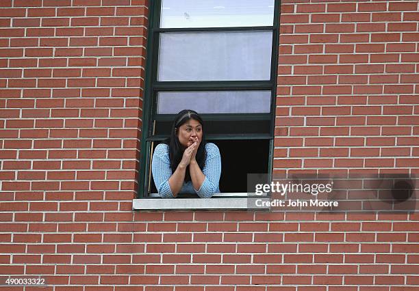 Woman watches from her apartment as Pope Francis departs the Lady Queen of Angels school on September 25, 2015 in New York City. The Pope visited the...