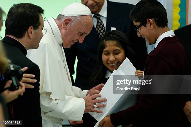 Pope Francis receives a book from Shaila Cuellar and Victor Franco during a visit Our Lady Queen of Angels School September 21, 2015 in the East...