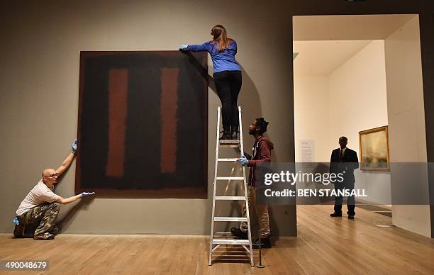 Security guard looks on as employees pose with a work of art by Russian born US artist Mark Rothko entitled 'Black on Maroon' 1958, during a...