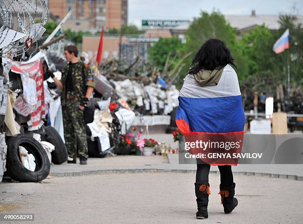 Woman wrapped in a Russian flag walks at a barricade outside the regional state building seized by separatists in the centre of the eastern Ukrainian...