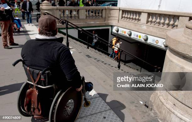 Disabled man in a wheelchair hands out flyers at the top of a metro station's stairs as he takes part in a demonstration called by the Paralysed...