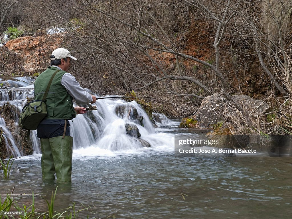 Fisherman in river trout fishing