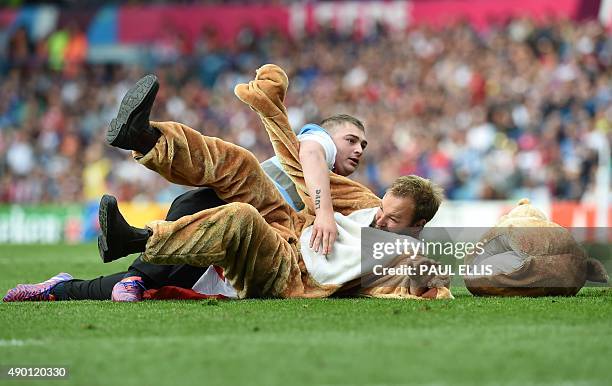 Steward tackles a costumed man who ran onto the pitch during a Pool D match of the 2015 Rugby World Cup between Italy and Canada at Elland Road in...