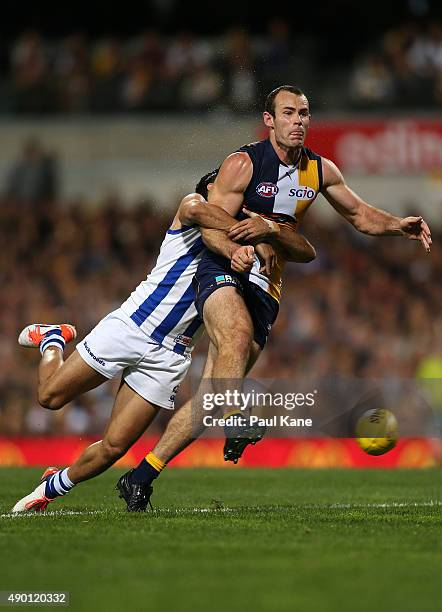 Shannon Hurn of the Eagles gets his kick away while being tackled by Lindsay Thomas of the Kangaroos during the AFL Second Preliminary Final match...