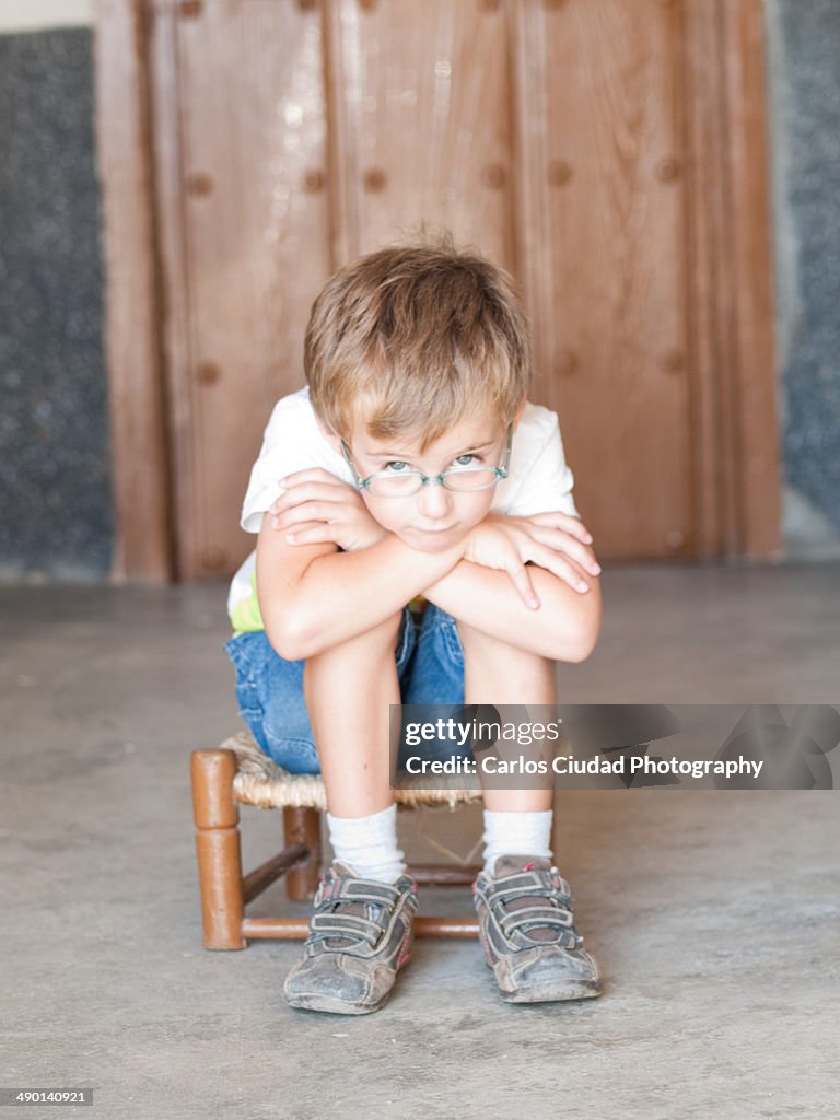 Sad child sitting on small chair